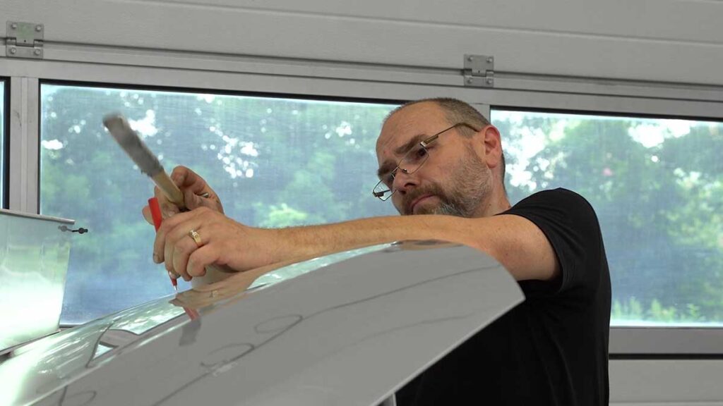 Technician gently reshapes a shallow door dent while inspecting the vehicle’s painted surface.